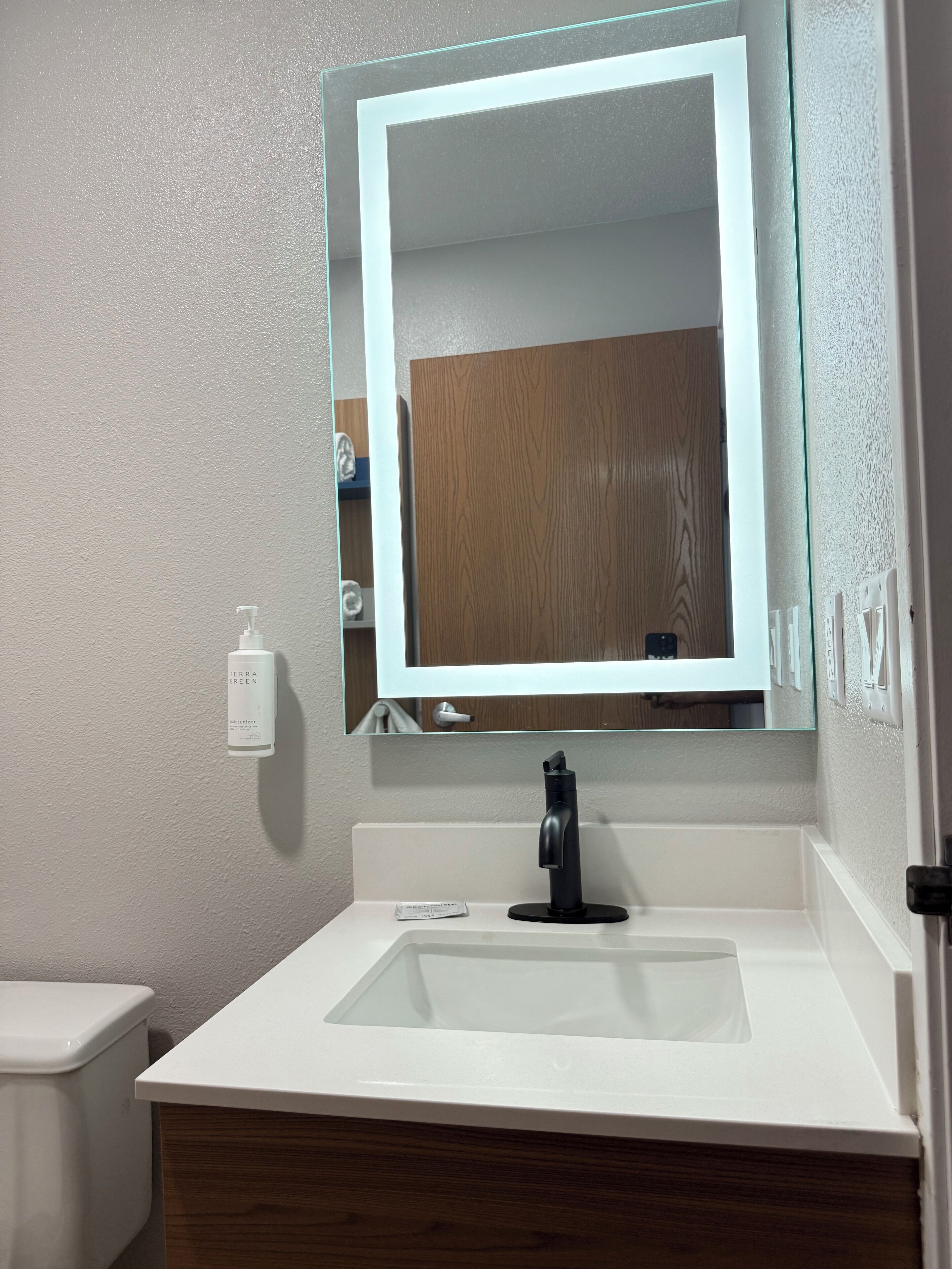 A bathroom with a white sink, a mirror, and a wooden cabinet.
