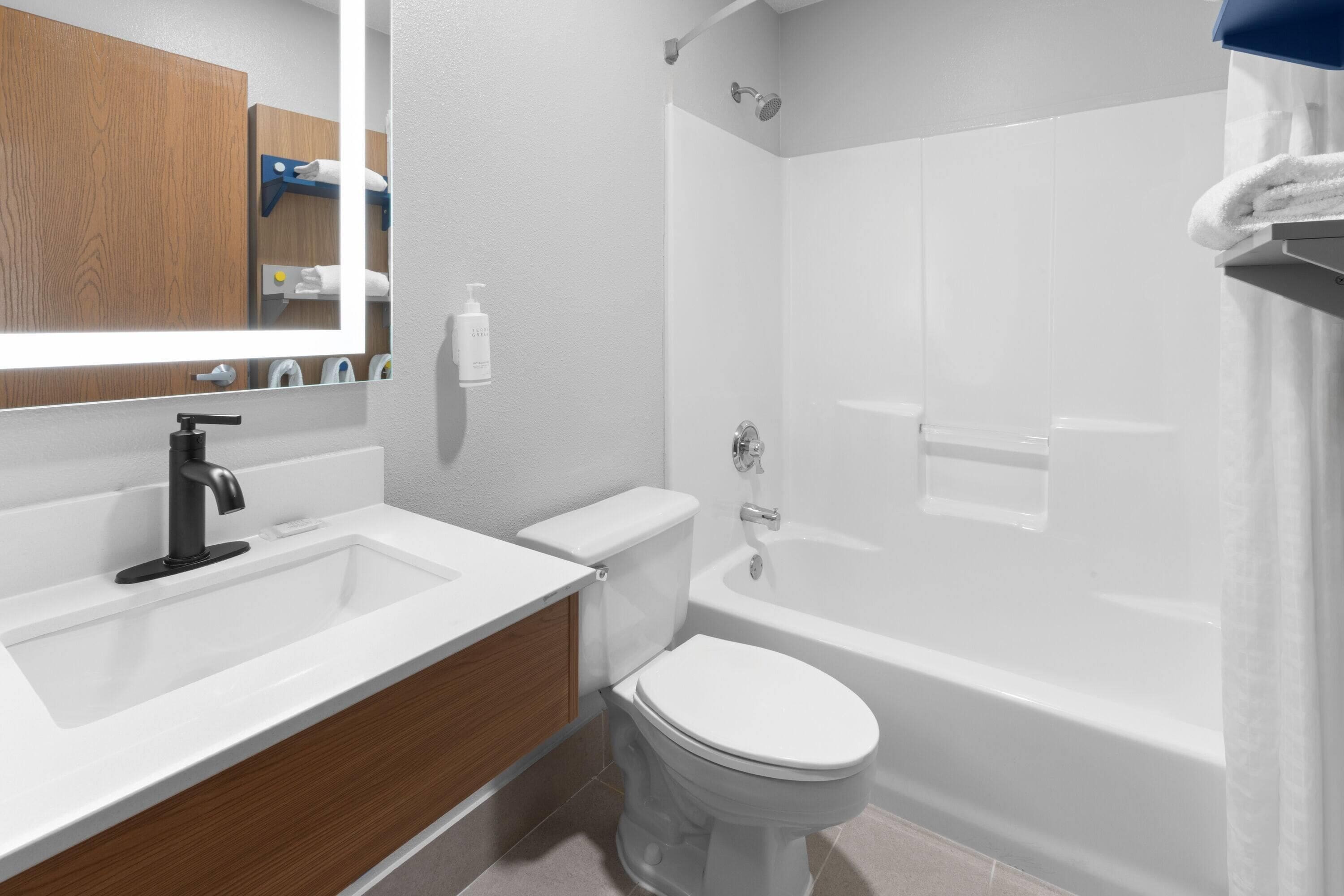 A modern bathroom with a white sink, vanity, toilet, and bathtub.