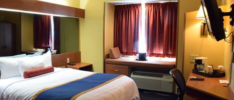 Une chambre d’hôtel équipée d’un lit, d’un bureau, d’une chaise et d’un grand miroir.