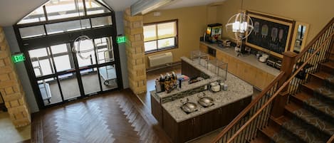 A spacious interior with a herringbone wood floor, a kitchen area with granite countertops, and a staircase with patterned carpet.