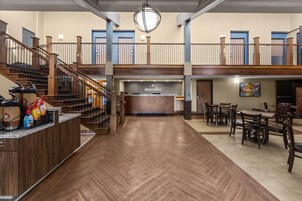 Un vestíbulo de hotel con una mesa de recepción, una estación de café y una zona de estar con mesas y sillas.