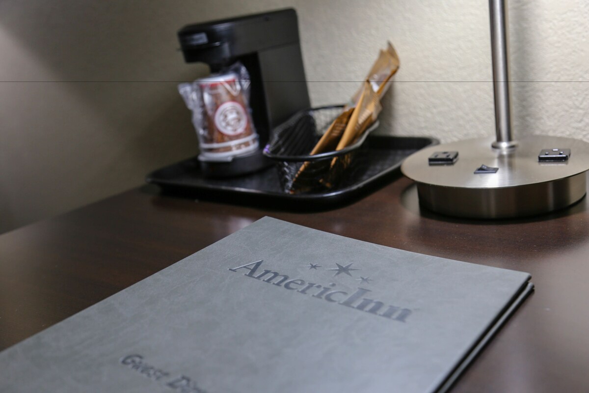 A table with a menu, a coffee machine, and a lamp.