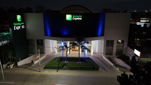 A Holiday Inn Express building with a modern design, featuring a central entrance with a blue-lit canopy and a landscaped garden area in front. - Holiday Inn Express Toluca by IHG (Toluca)