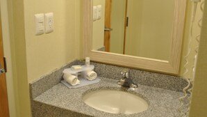 Baño con encimera de granito, lavamanos blanco, espejo y perchero.