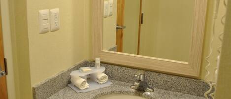 Baño con encimera de granito, lavamanos blanco, espejo y perchero.