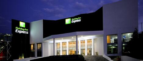 Un edificio de Holiday Inn Express con diseño moderno, grandes ventanales y una entrada destacada.