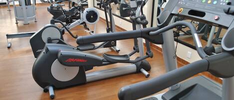 Un gimnasio con equipos de ejercicio variados, incluyendo cintas de correr y bicicletas estáticas.