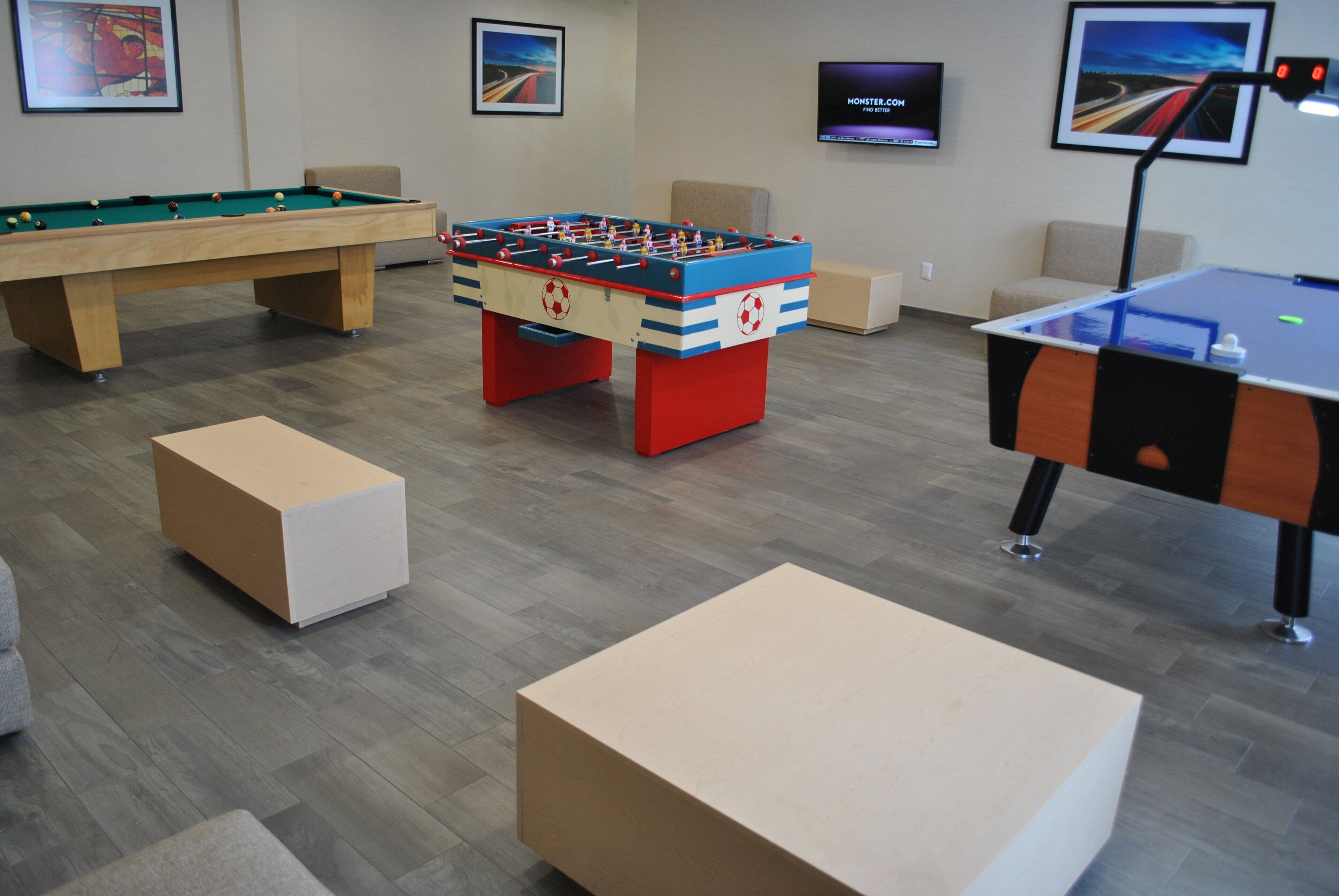A room with a foosball table, a pool table, and a ping pong table.