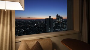 A hotel room with a large window overlooking a cityscape at dusk. - Century Southern Tower Hotel (Tokyo)