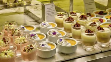 Diversos postres exhibidos sobre una encimera de mármol, incluyendo mousse de chantilly y mousse de chocolate, cada uno decorado con detalles ornamentales.