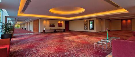 Un amplio vestíbulo de hotel con alfombra de estampado rojo, mobiliario moderno y una zona de estar amplia.