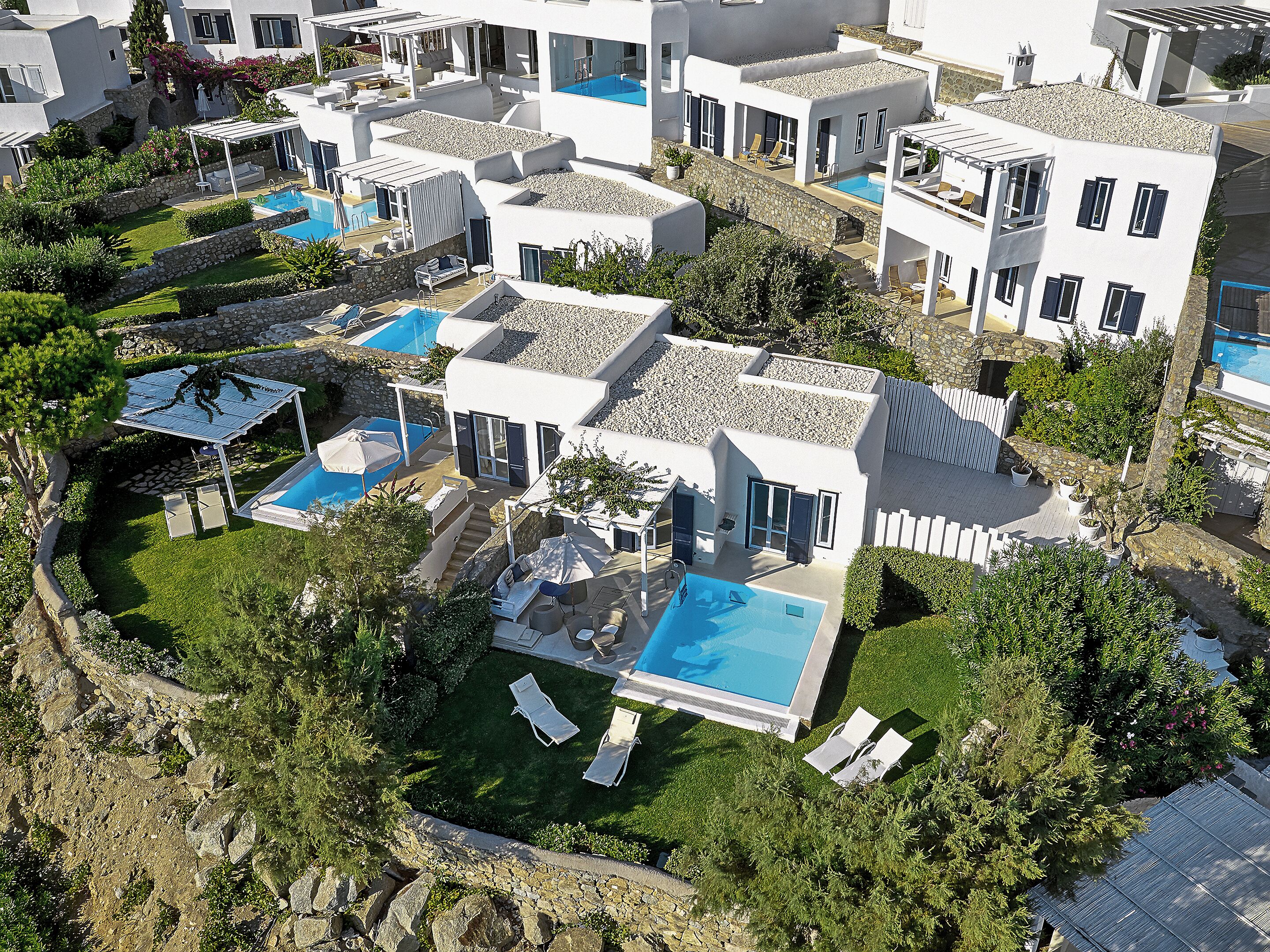 A resort with multiple swimming pools, white buildings, and lush greenery.