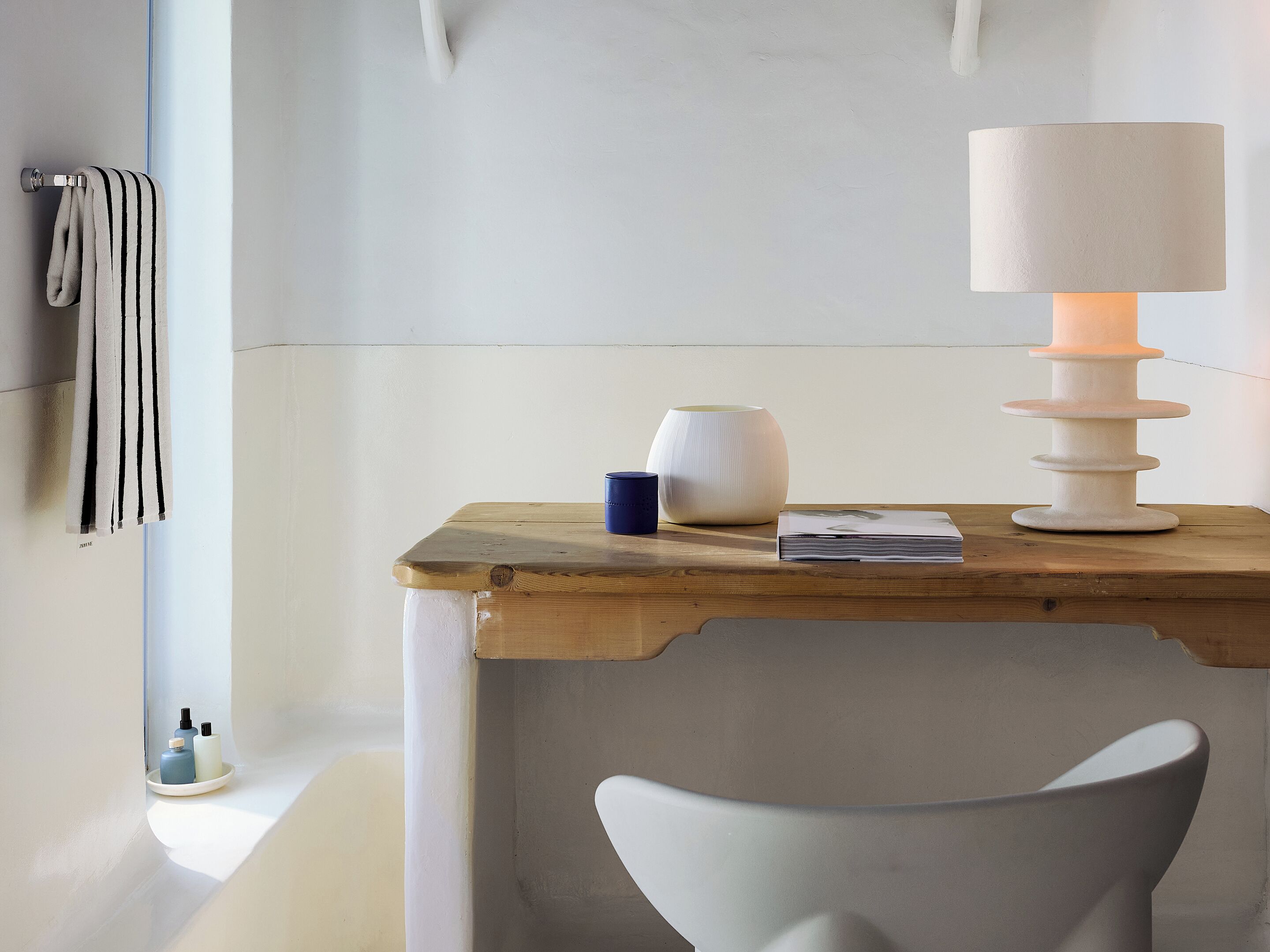 A wooden table with a white lamp, a vase, and a book.
