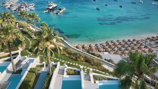 A resort with multiple swimming pools, a beach area with umbrellas, and boats in the water.
