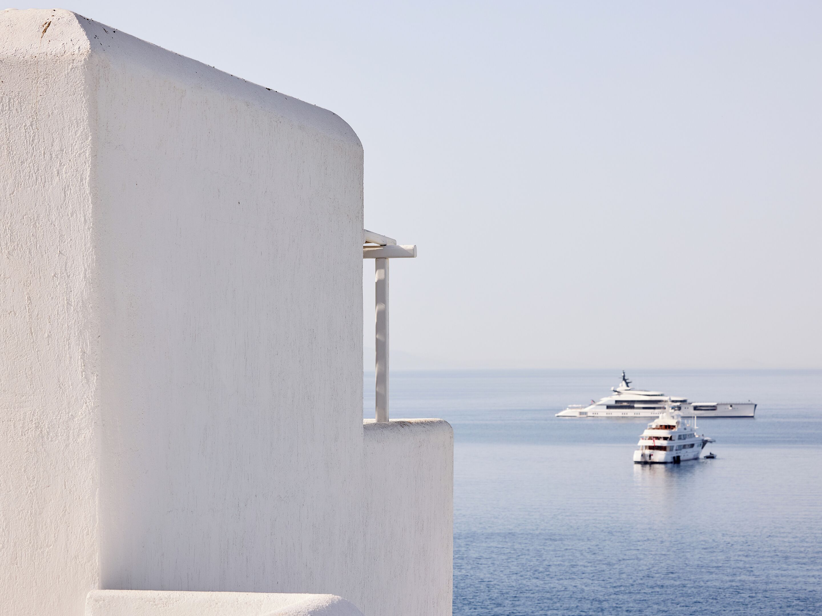 A white building with a balcony overlooking calm sea waters.