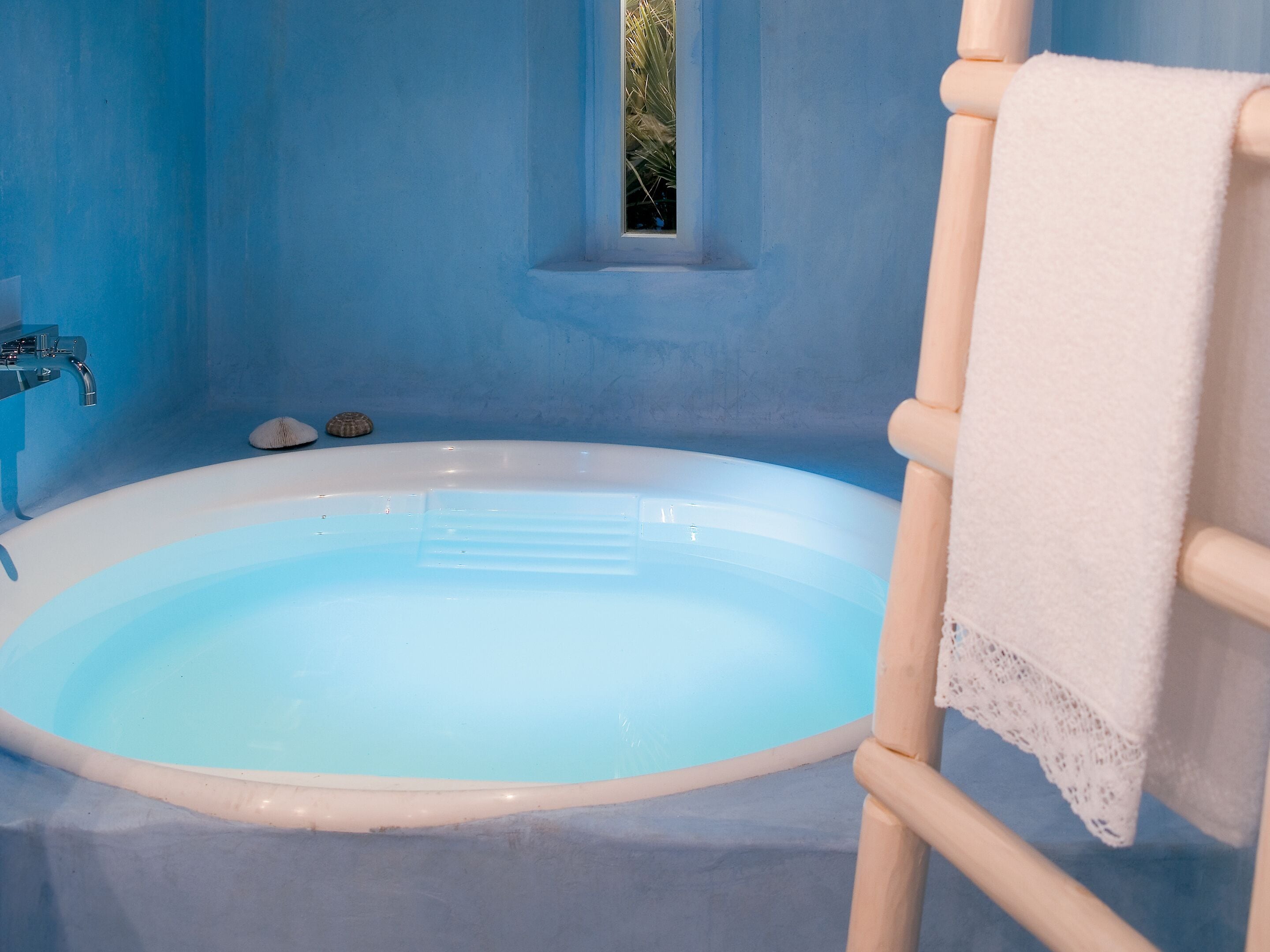 A bathtub with a white towel hanging on a wooden rack.