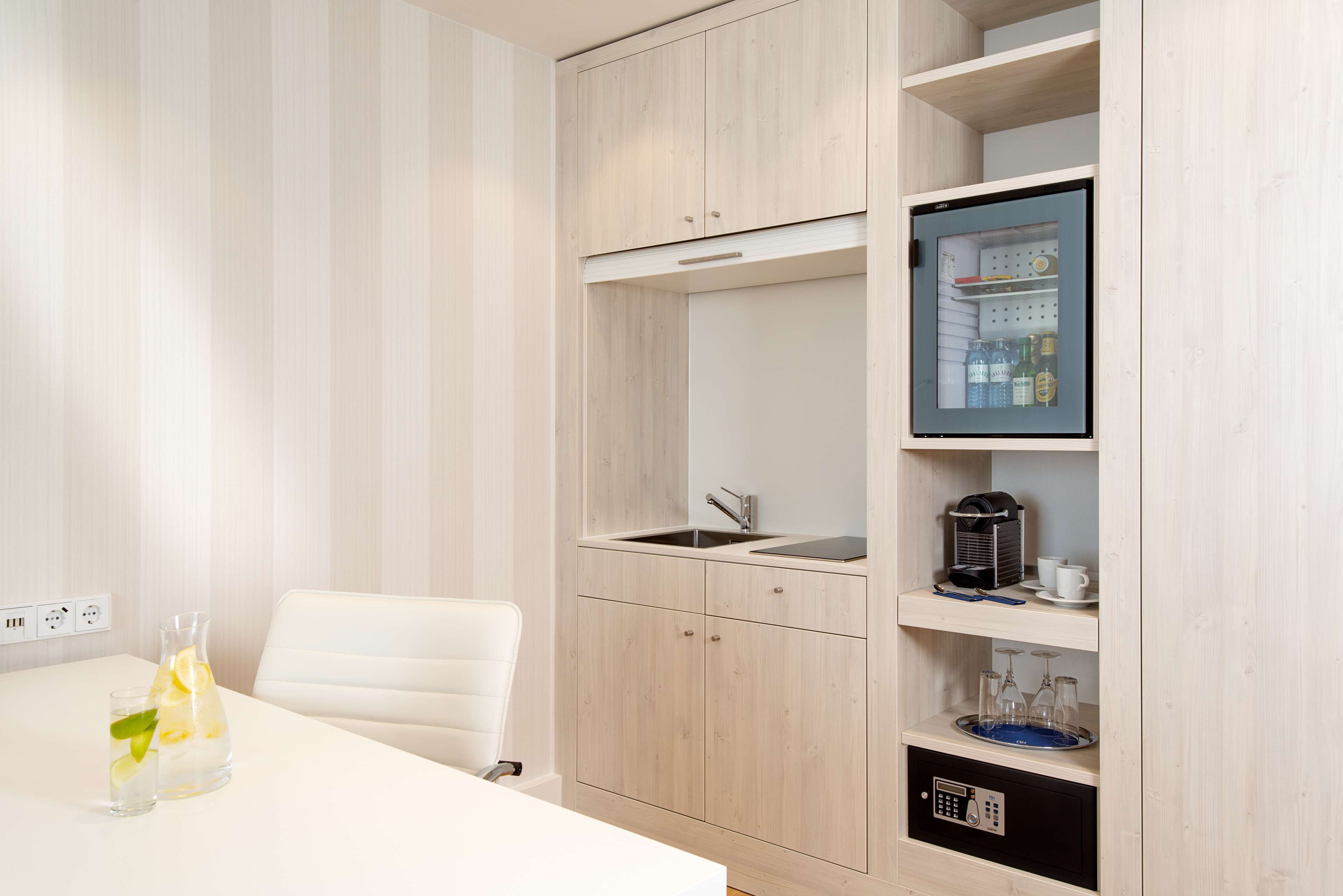A compact kitchenette with a built-in fridge, a sink, and a small countertop.