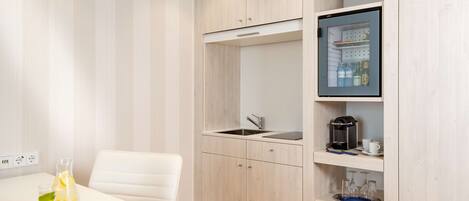 A compact kitchenette with a built-in fridge, a sink, and a small countertop.
