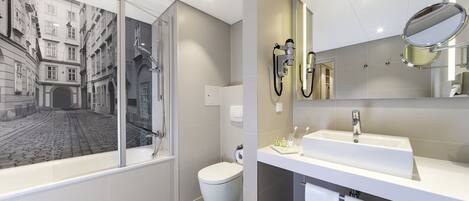 Un baño moderno con un ventanal grande, una bañera, un inodoro, un lavabo y un espejo.