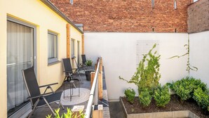 A balcony with outdoor furniture, a brick wall, and a garden area. - Best Western Hotel Nuernberg Am Hauptbahnhof (Nuremberg)