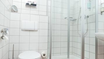Ein modernes Badezimmer mit einer gläsernen Duschkabine, einer Toilette und einem Waschbecken.