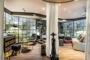 A modern living room with a curved ceiling, large windows, and a variety of seating options including a sofa, armchairs, and a chair. - Best Western Hotel Nuernberg Am Hauptbahnhof (Nuremberg)