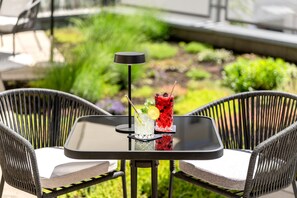 Una mesa con dos sillas, dos bebidas y una lámpara negra.