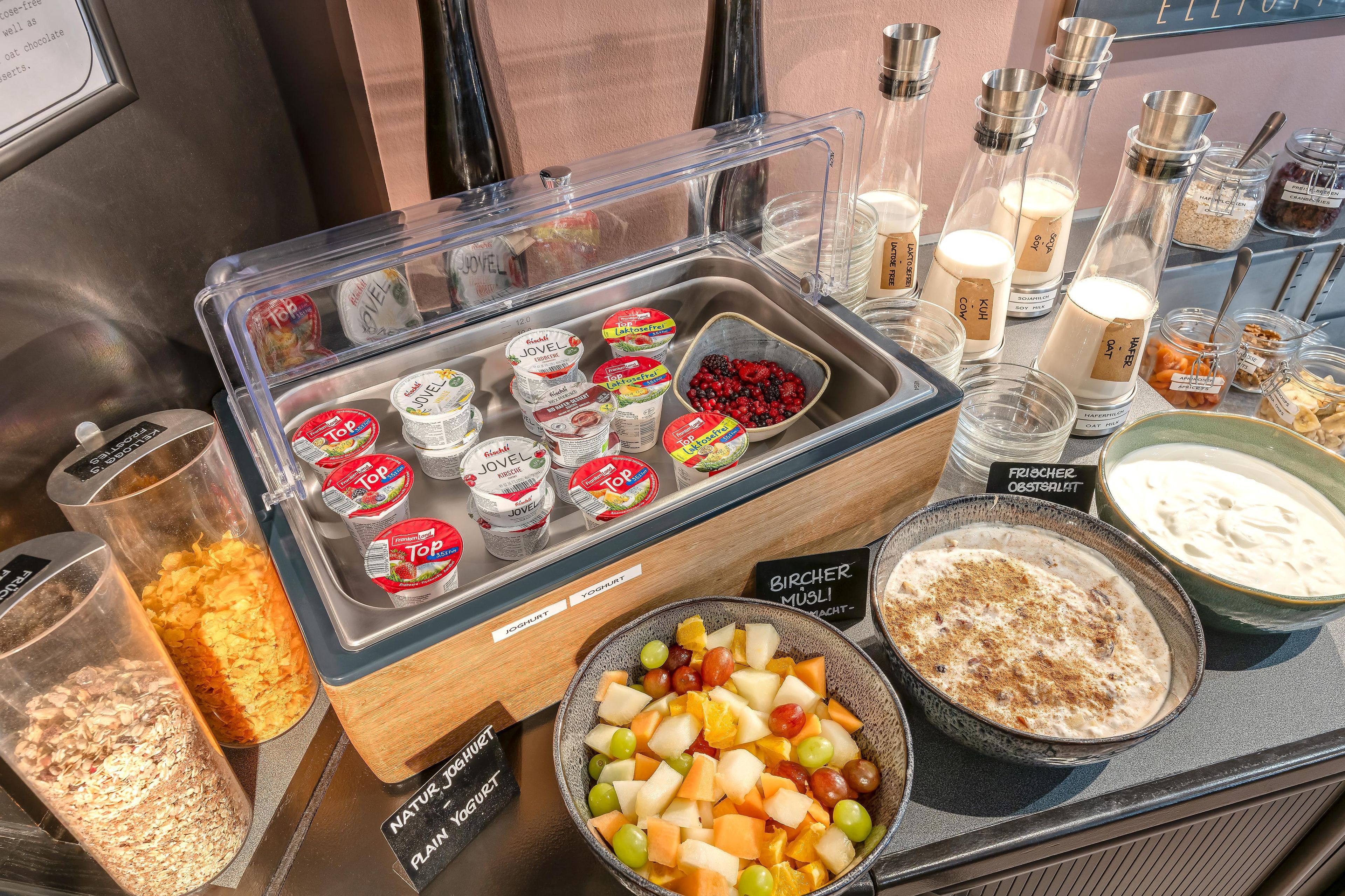 A variety of food items including yogurt, fruits, and desserts in a display case.