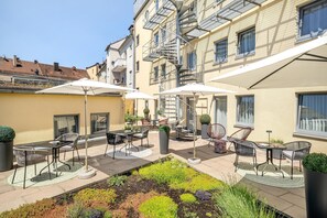 A courtyard with outdoor seating, a garden, and a building with a fire escape. - Best Western Hotel Nuernberg Am Hauptbahnhof (Nuremberg)