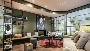 A modern living room with a large window, a bookshelf, a sofa, and a coffee table. - Best Western Hotel Nuernberg Am Hauptbahnhof (Nuremberg)