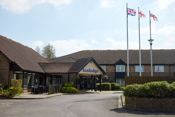 A hotel named Innodge with a traditional brick facade, a covered entrance, and three flags. - Farmhouse Innlodge by Greene King Inns (Portsmouth)
