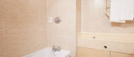 A bathroom with a bathtub, toilet, and a towel rack.