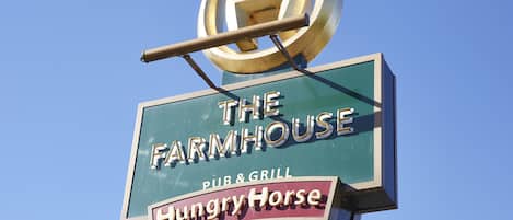 A sign for "The Farmhouse Pub & Grill" with a "Hungry Horse" logo and a "Great Value Pub" sign below.