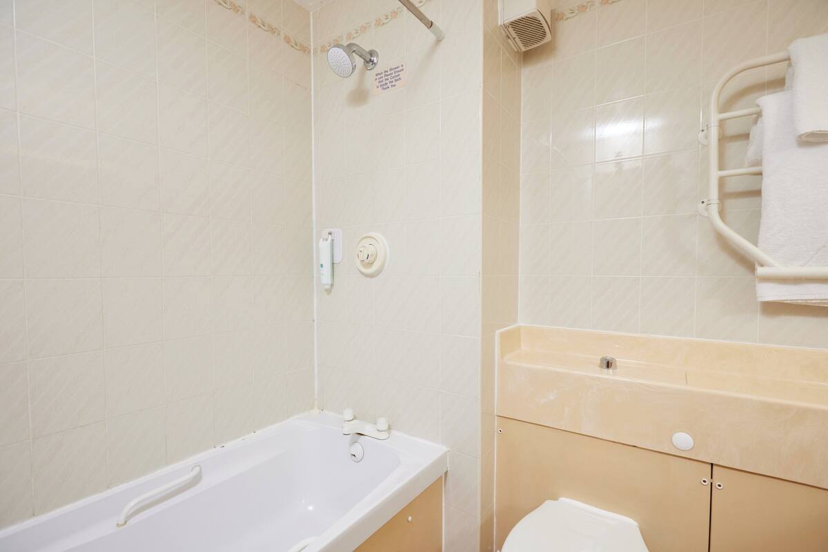 A bathroom with a bathtub, a shower, a toilet, and a towel rack.