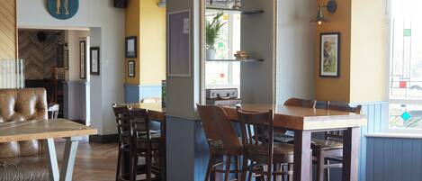 Interno di un ristorante con un bancone in legno, sedute in pelle e un globo appeso al muro.