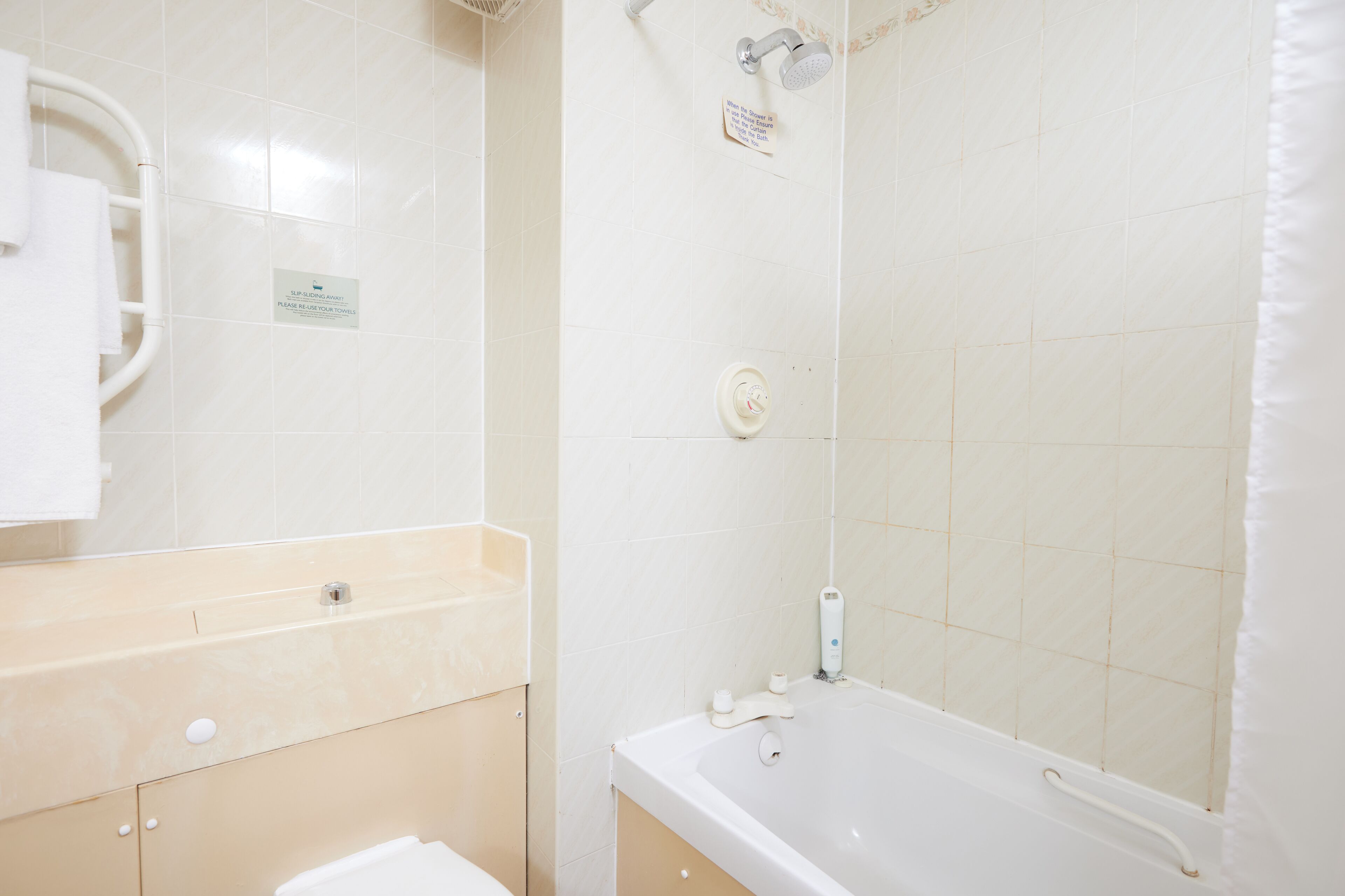 A bathroom with a bathtub, a towel rack, and a hand dryer.