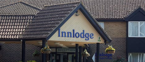 A hotel named Inn Lodge with a tiled roof, a reception area, and a signboard.