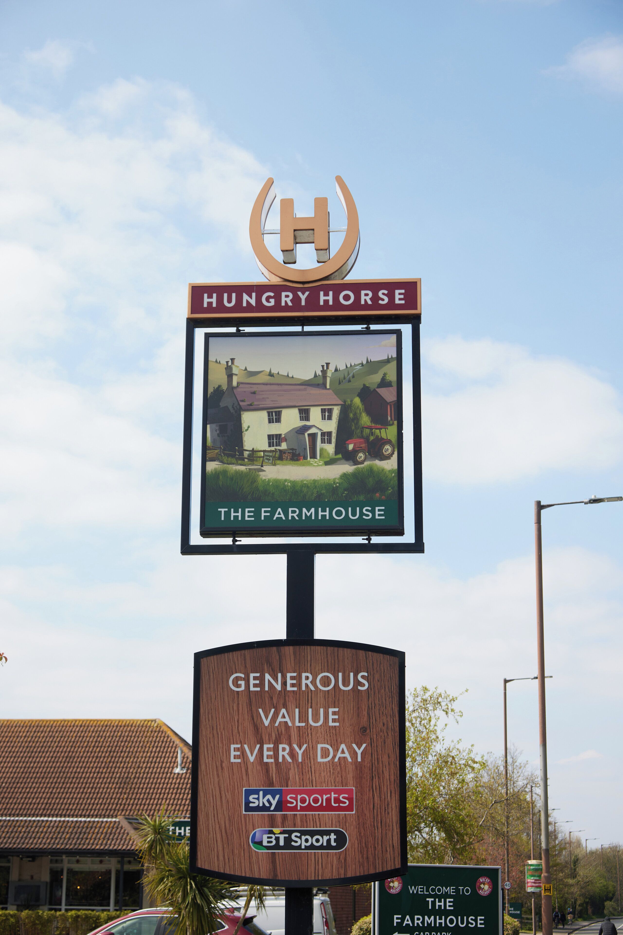 A sign for Hungry Horse The Farmhouse with a logo and a picture of a house.