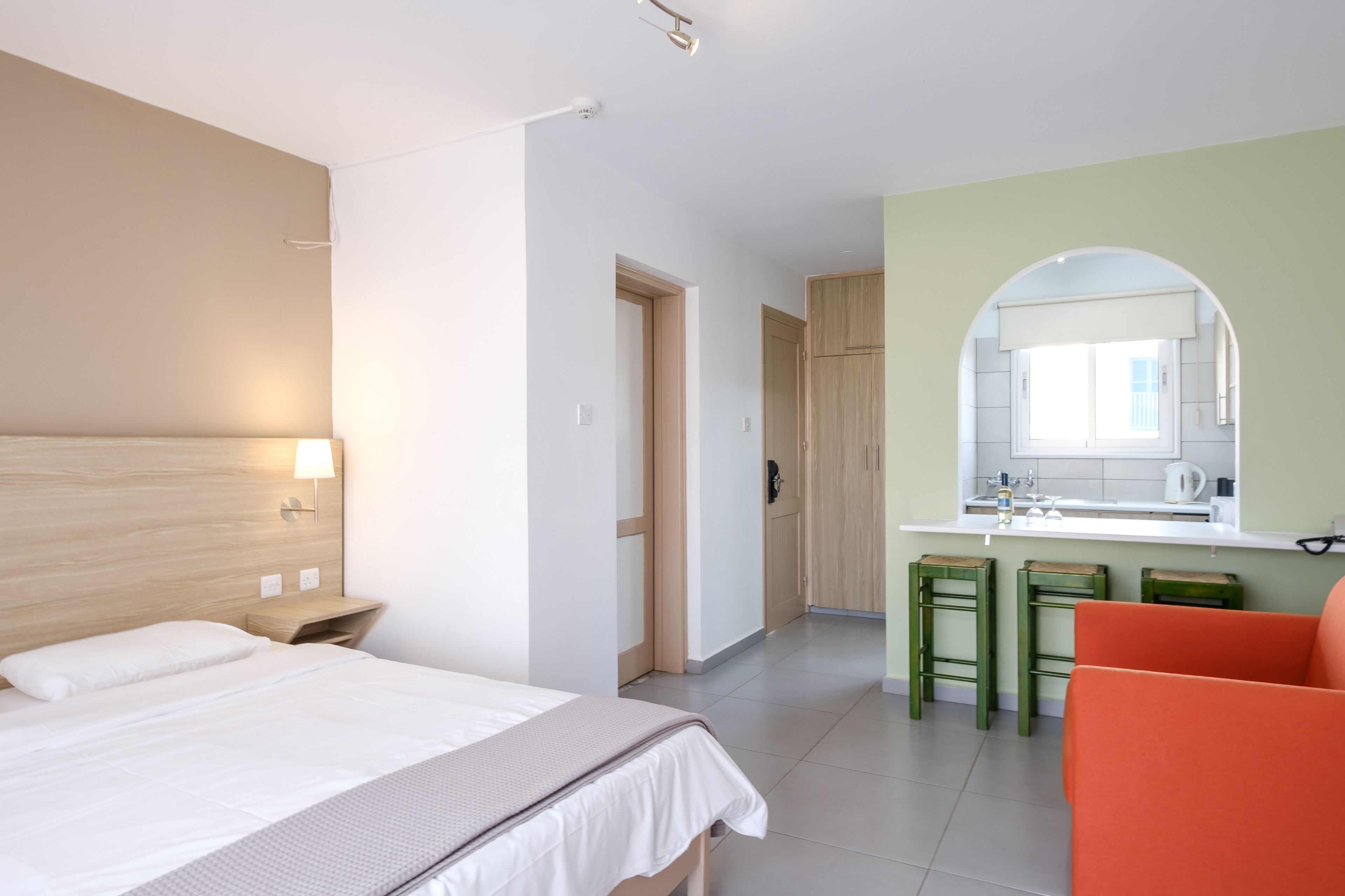 A hotel room with a bed, a small kitchenette, and a bathroom.