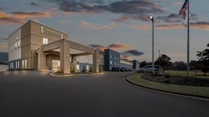 Un hotel Staybridge Suites con un diseño moderno, una entrada cubierta y un asta con la bandera estadounidense.