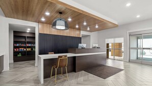Una cocina moderna con techo de madera, encimera blanca y una zona de bar con un taburete.