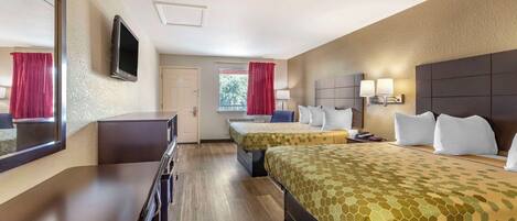 A hotel room with two beds, a desk, a TV, and a window with curtains.