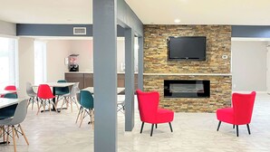 Un intérieur moderne avec une cheminée en pierre, des fauteuils rouges et un téléviseur à écran plat fixé au mur.