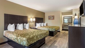 Une chambre d’hôtel avec deux lits, un bureau et une salle de bain que l’on aperçoit à l’arrière-plan.
