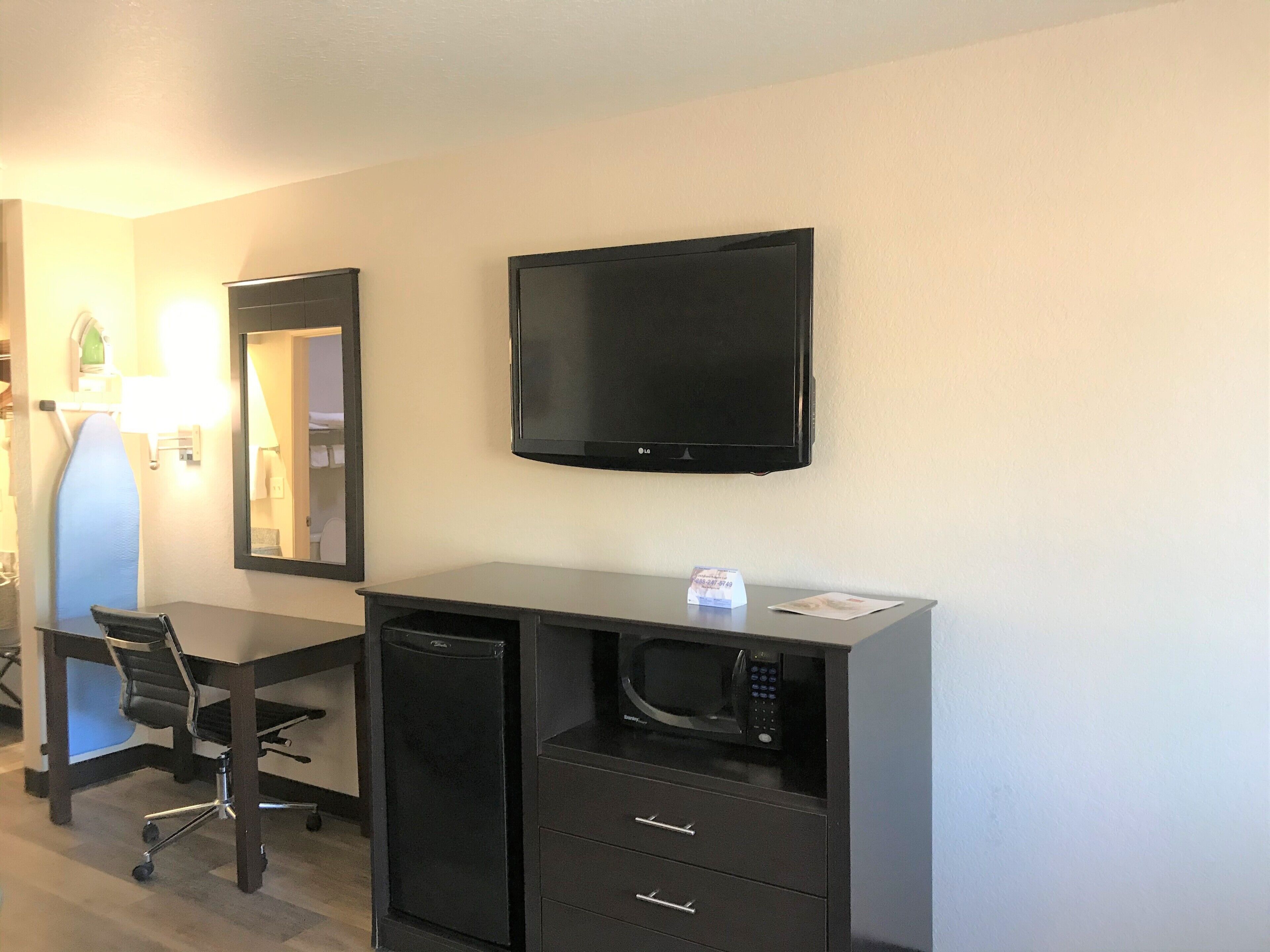 Habitación de hotel con escritorio, silla, microondas y televisión de pantalla plana.
