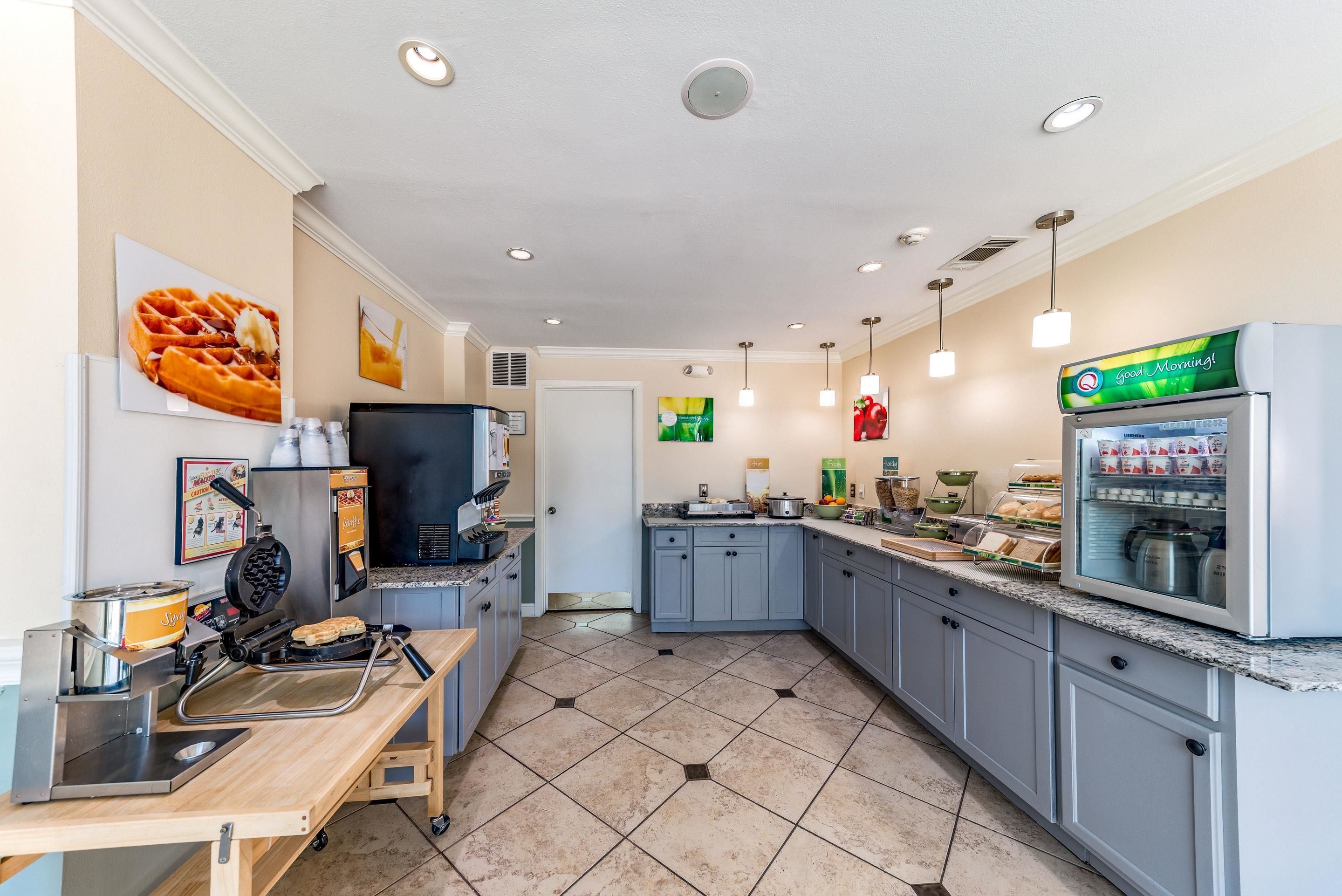 A kitchen with a waffle maker, a coffee machine, and a refrigerator.