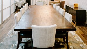 A conference room with a long wooden table, white upholstered chairs, a chandelier, a flat-screen TV mounted on the wall, and a bookshelf with decorative items. - Hotel Indigo San Antonio Riverwalk by IHG (San Antonio)