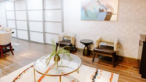 A modern lobby with a glass coffee table, two armchairs, a small round table, and a large abstract painting on the wall. - Hotel Indigo San Antonio Riverwalk by IHG (San Antonio)