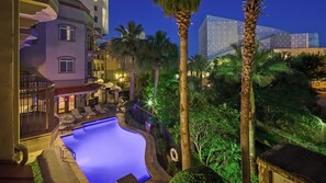 A hotel with a swimming pool, palm trees, and a modern building in the background. - Hotel Indigo San Antonio Riverwalk by IHG (San Antonio)