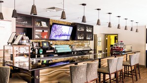 A bar area with a long counter, multiple bar stools, and a television screen. - Hotel Indigo San Antonio Riverwalk by IHG (San Antonio)